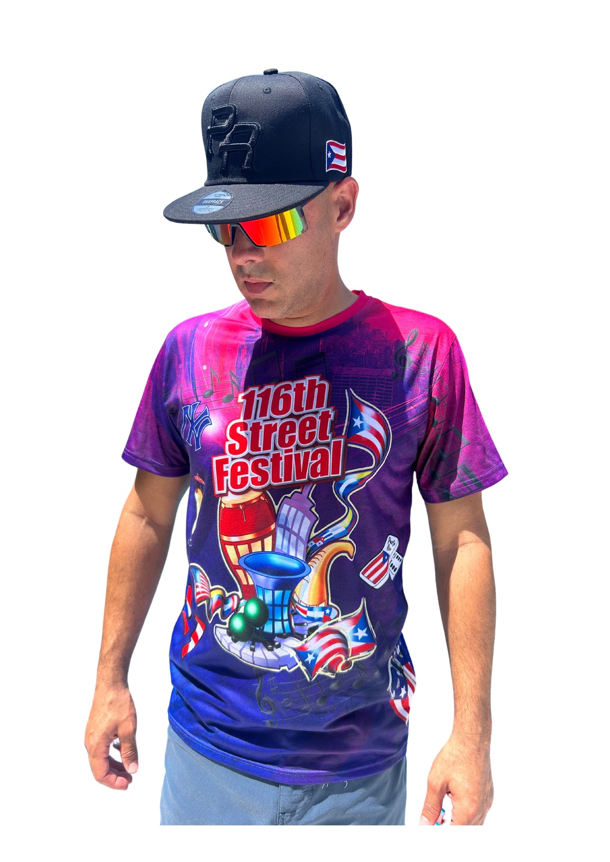 Person wearing a colorful t-shirt with '116th Street Festival' design, navy cap, and rainbow sunglasses on a white background.