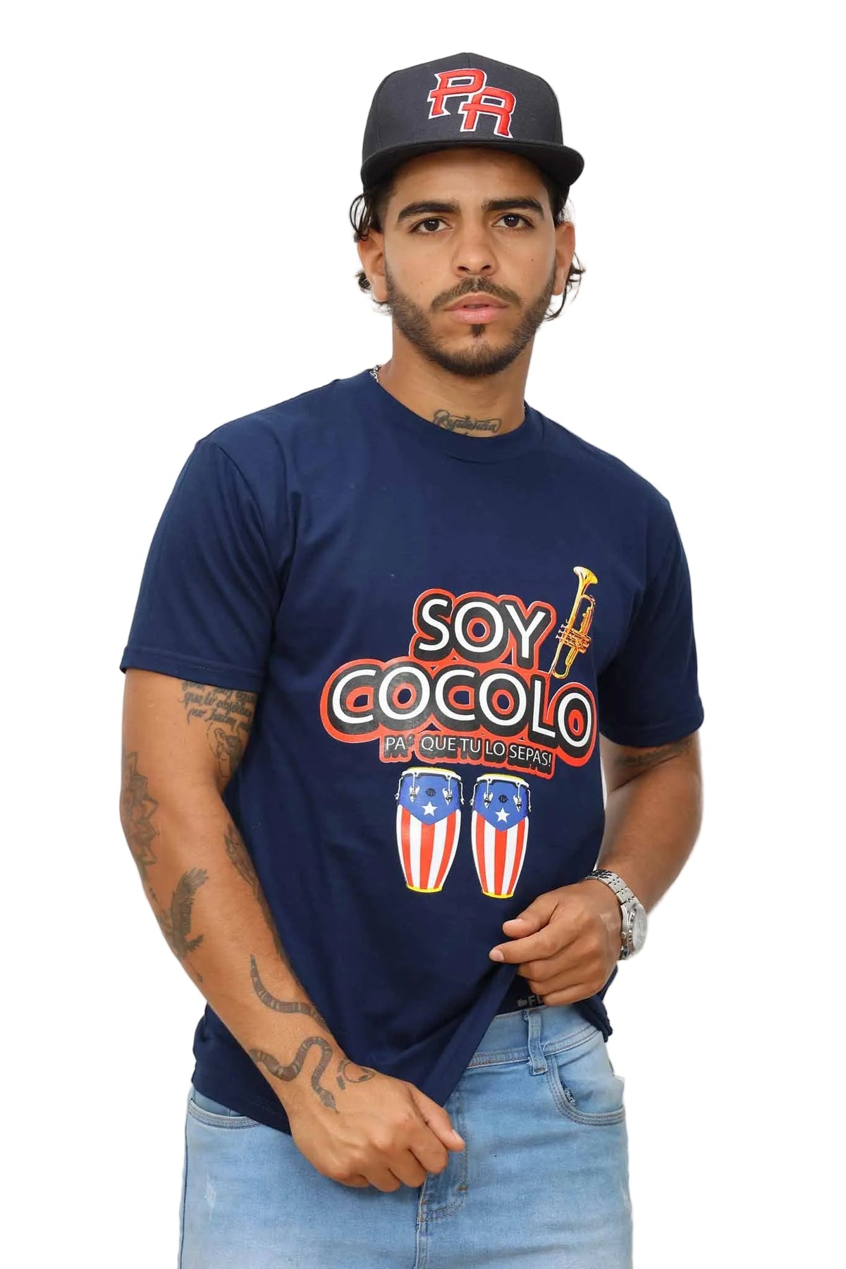 Man wearing a navy blue t-shirt with 'Soy Cocolo' text and graphics, standing against a white wall.