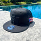Black cap with a Puerto Rican flag design on a poolside surface